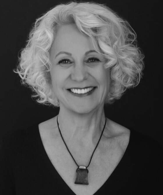 Irene Ziegler smiling, in a black top and orange pendant